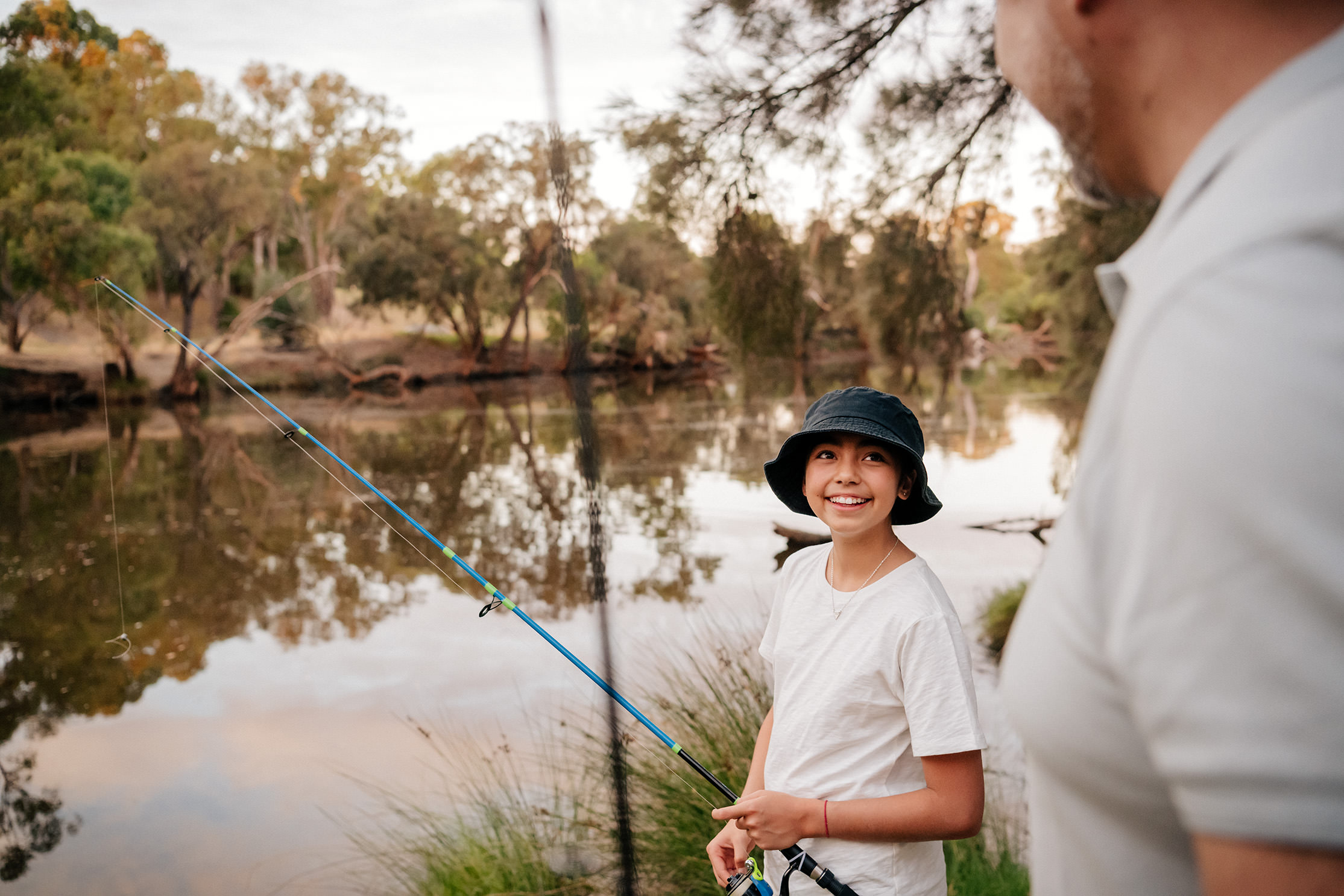 father and son fishing by the riverside in rivermark